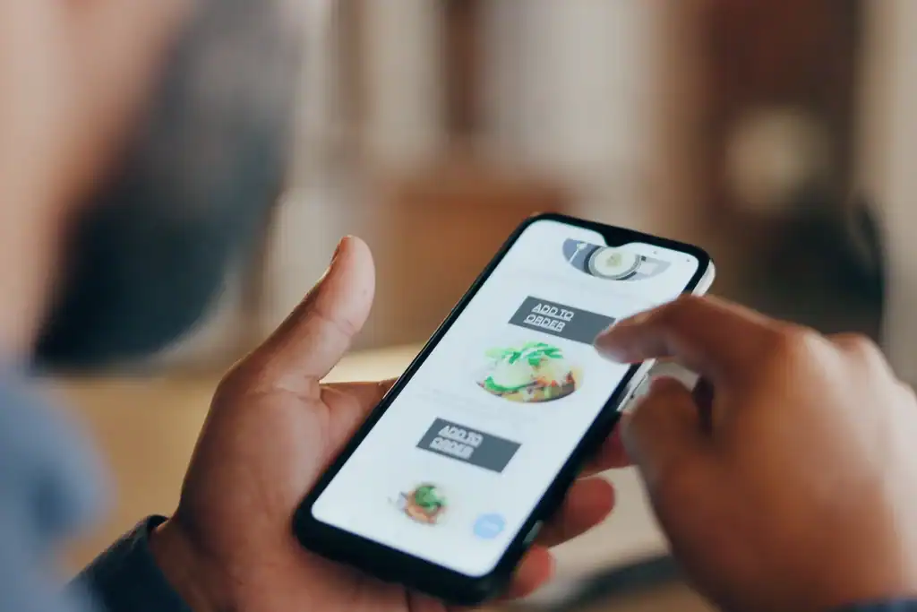 Close-up of a person using a smartphone to place a food order through a restaurant mobile app, highlighting tech & AI convenience in dining.