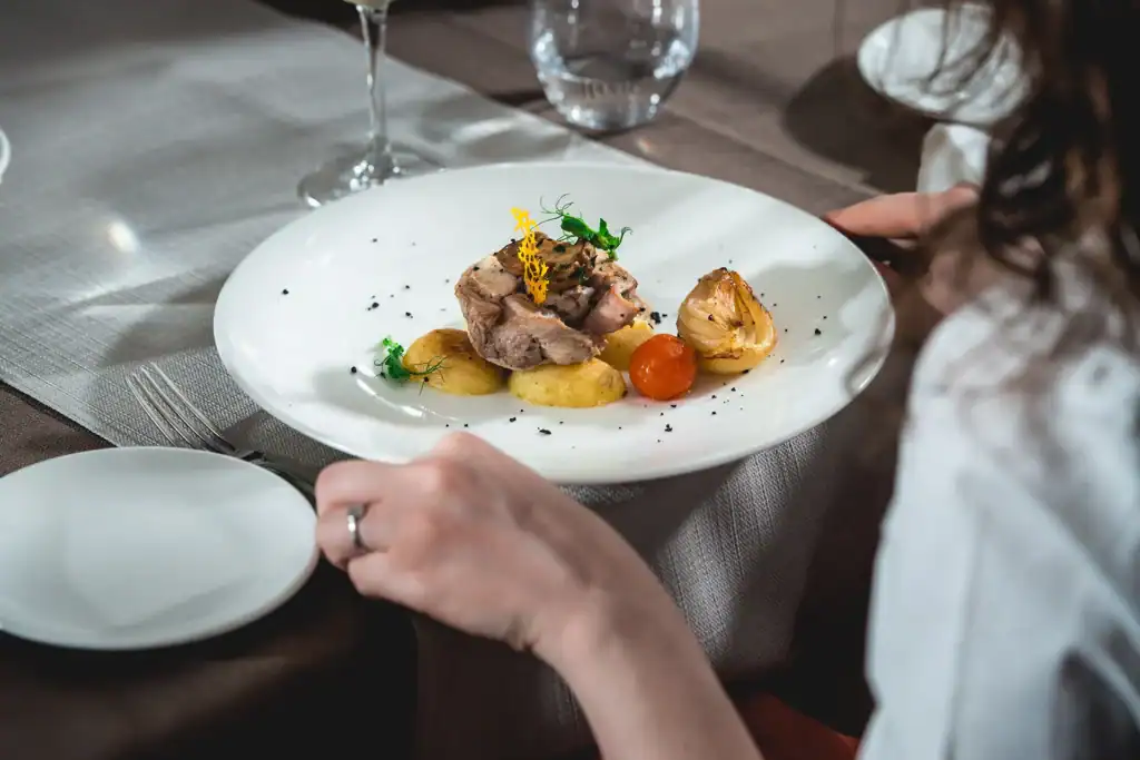 Person preparing to eat small-portion, health-conscious meal by grabbing fork & knife.